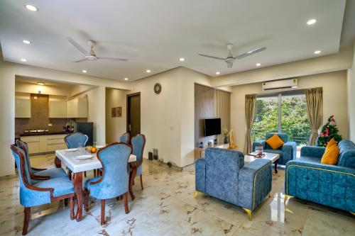 Premium 2BHK Apartment with pool at Candolim Beach في كاندوليم: غرفة معيشة مع كراسي زرقاء وطاولة