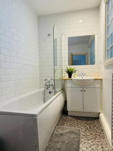 a white bathroom with a tub and a sink at Modern house in central St Leonards in Hastings