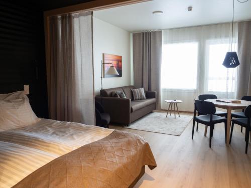a bedroom with a bed and a couch and a table at Nallikari Seaside Aalto Apartments in Oulu