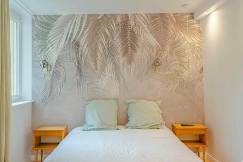 une chambre avec un lit avec un mur avec des feuilles de palmier dans l'établissement Petit Appartement Cosy proche Centre historique, à Caen