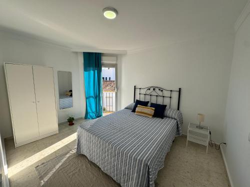 a bedroom with a bed with blue curtains in it at Encantadora casa en el corazón de Estepona in Estepona