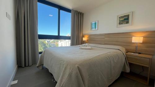 a bedroom with a bed and a large window at Michelangelo 806 in Punta del Este