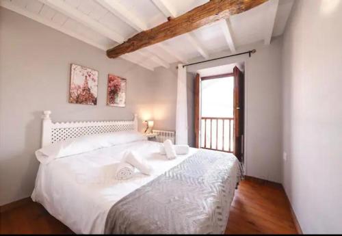 a white bedroom with a large white bed with a window at La Casina de la Peña in Luarca