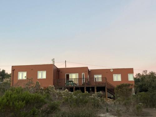 une maison en bois avec une terrasse dans le désert dans l'établissement Casa en Algarrobo, parcela en sector Mirasol, à Algarrobo