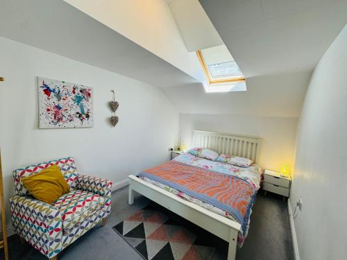 a small bedroom with a bed and a chair at The Old Queens Stable on Sea in Hollington