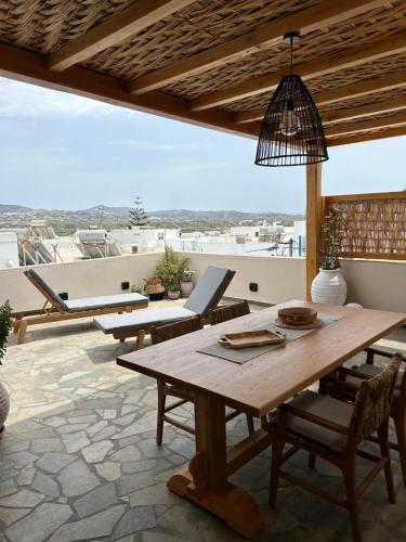 a patio with a wooden table and chairs on a roof at Naxian Icon Luxury Residence in Naxos Chora