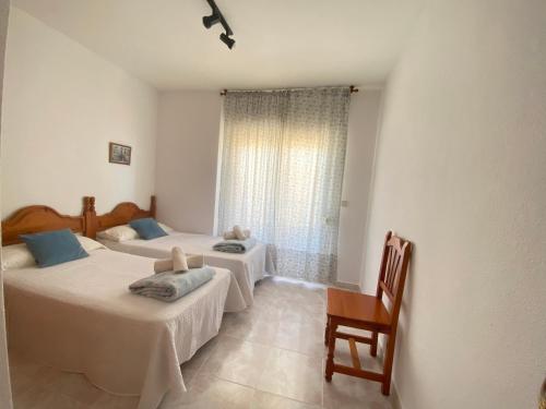 1 dormitorio con 2 camas, silla y ventana en Apartamentos Copacabana Playa, en La Manga del Mar Menor