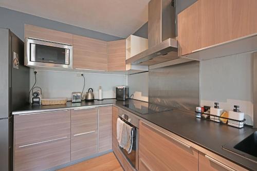 une cuisine avec des appareils en acier inoxydable et des armoires en bois dans l'établissement O'portes de la gare-parking-clim-5mins centre-ville, à Avignon