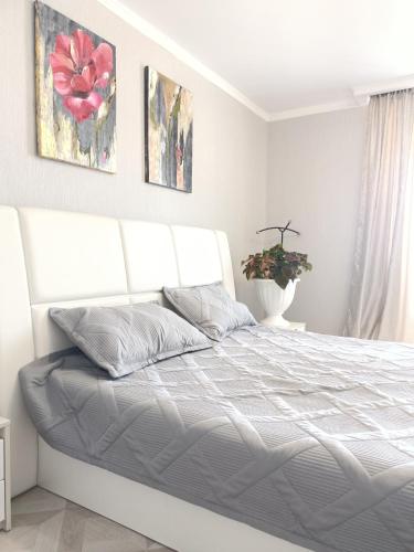 ein weißes Bett in einem weißen Schlafzimmer mit einem weißen Bettrahmen in der Unterkunft 2-х комнатная квартира посуточно in Kökschetau