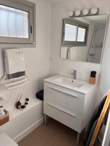 une salle de bain blanche avec un lavabo et un miroir dans l'établissement villa plage les Sables d’Olonne, à La Chaume