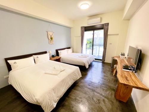 a hotel room with two beds and a television at 阿郎衝浪旅店A-lang Surfing House in Manzhou