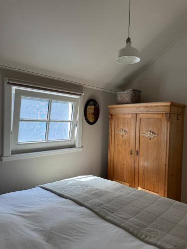 a bedroom with a bed and a window and a wooden cabinet at HAVENZICHT HUISJE, chique ingericht, compleet uitgerust, prachtig uitzicht! in Belt-Schutsloot