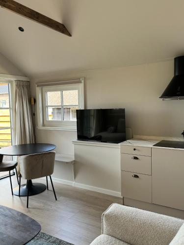 a living room with a table and a tv at HAVENZICHT HUISJE, chique ingericht, compleet uitgerust, prachtig uitzicht! in Belt-Schutsloot