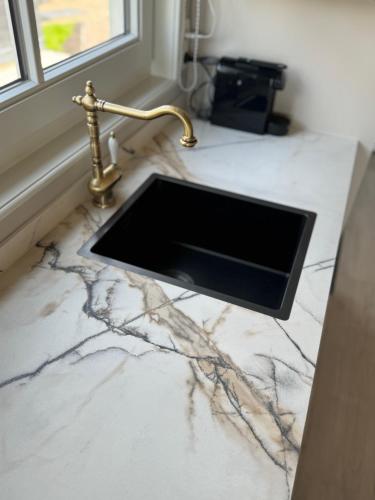 a kitchen counter with a sink and a gold faucet at HAVENZICHT HUISJE, chique ingericht, compleet uitgerust, prachtig uitzicht! in Belt-Schutsloot