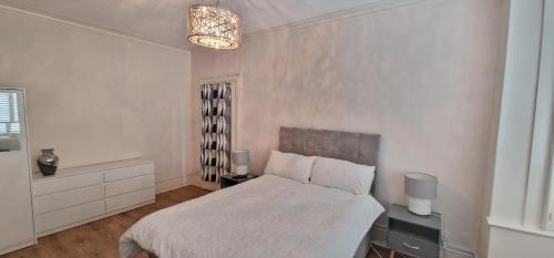 a white bedroom with a bed and a chandelier at Charming Catford Home: Explore South London's Best Attractions! in Catford