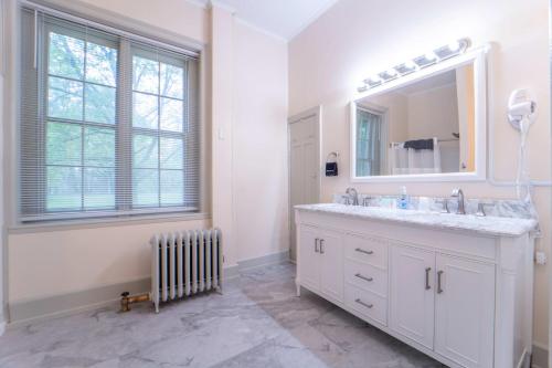 a white bathroom with a sink and a mirror at Oneida Community Mansion House in Oneida