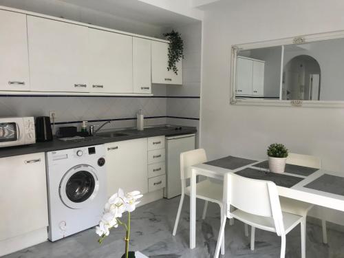a kitchen with a washing machine and a table with chairs at Beach Side Heaven in Fuengirola