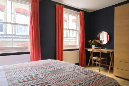 a bedroom with red curtains and a table and a bed at Clerkenwell Premium Deluxe in London