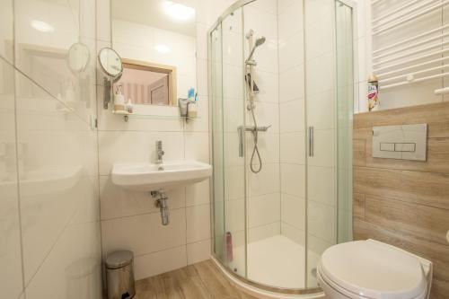 a bathroom with a shower and a toilet and a sink at Piaskowe Domki in Grzybowo