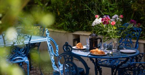 a blue table with a vase of flowers and bread at The Old School Rooms Beautiful Georgian apartment, sleeps 12 with Wifi and Parking, near Bath in Box