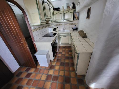 una pequeña cocina con armarios blancos y suelo de baldosa. en 481-Villa Kerdreal Proche plage, en Audierne