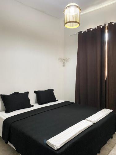 a bedroom with a large bed with black and white sheets at Quarto de Solteiro Uberaba in Uberaba