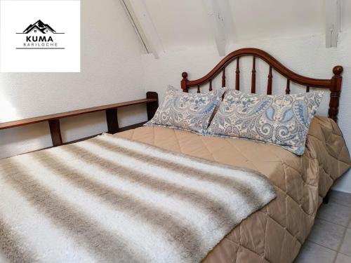 a bed with a wooden headboard and pillows on it at Cabaña Kuma Bariloche Barrio Melipal in San Carlos de Bariloche