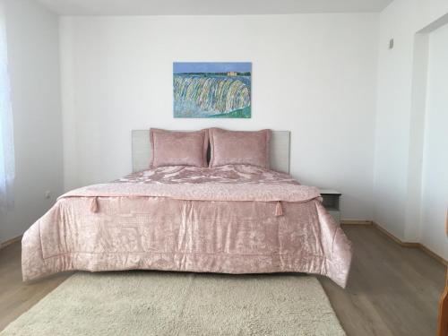 een slaapkamer met een bed met een roze dekbed bij Апартамент 170 кв.м за 6-ма, село Ягодово, Пловдивско in Plovdiv