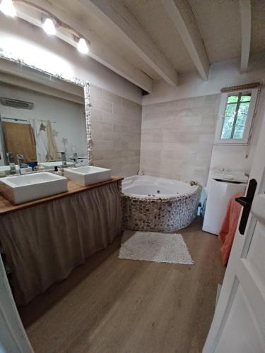 ein großes Badezimmer mit zwei Waschbecken und einer Badewanne in der Unterkunft Maison climatisée en campagne, terrasses couvertes grand jardin ombragé et piscine in Aix-en-Provence