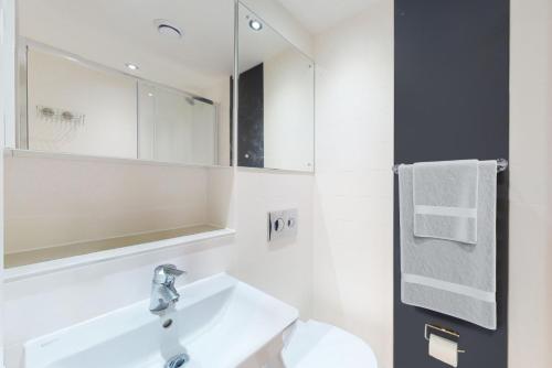 Baño blanco con lavabo y espejo en Private Bedrooms with Shared Kitchen, Studios and 2 Bed Apartments at Canvas Manchester en Mánchester