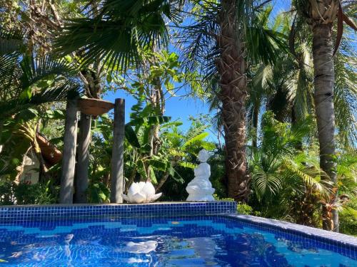 a swimming pool with two statues next to palm trees at Finca Los Caballos Montezuma in Montezuma