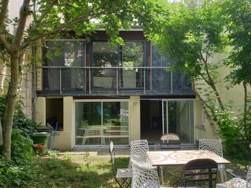 une maison avec une table et des chaises dans une cour dans l'établissement Maison 150m2 jardin à louer en entier, Bordeaux centre Chartrons, 3 Chambres 3 Salles de bains 1 canapé-lit llllnuméro de téléphone dans l'annonce si questionlll, à Bordeaux