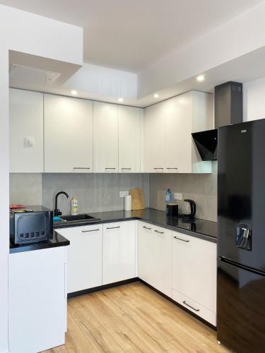 a kitchen with white cabinets and a black refrigerator at Apartamenty Przemyśl BG in Przemyśl