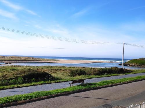 a bench on the side of a road looking at the ocean at Apartamento O lago in Valdoviño