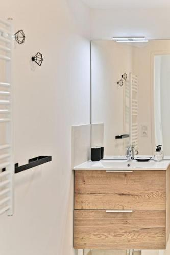 une salle de bain avec un lavabo et un miroir dans l'établissement Appartement 3 Chambres Mairie Saint-Ouen, à Saint-Ouen