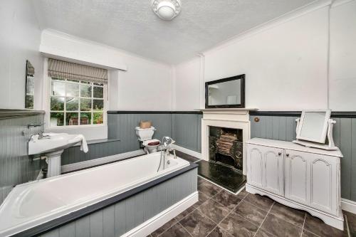 a bathroom with a tub and a sink and a fireplace at Finest Retreats - Low Green Cottage in Catterick Bridge
