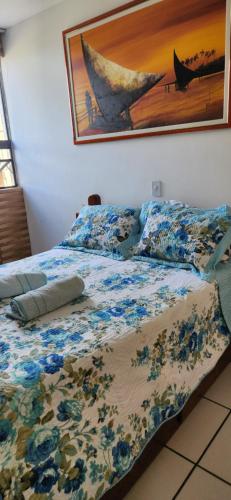 a bed with a comforter and a picture of a boat at EDIFÍCIO METROPOLE ONDINA in Salvador