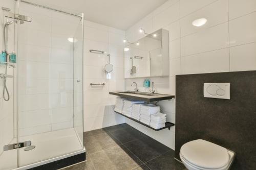 uma casa de banho com um chuveiro, um WC e um lavatório. em Appartement met zeezicht in Bloemendaal em Bloemendaal