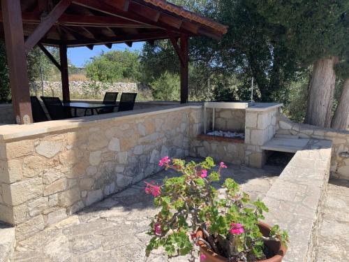 a patio with a stone wall and a bench and flowers at Carlas House, Kalyves in Tsivarás