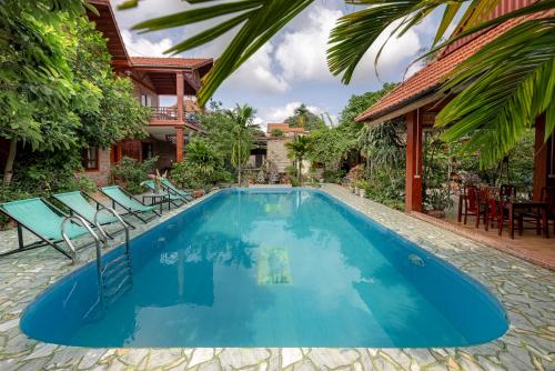 寧平的住宿－Trang An Family Homestay，一个带椅子的蓝色游泳池以及一座房子