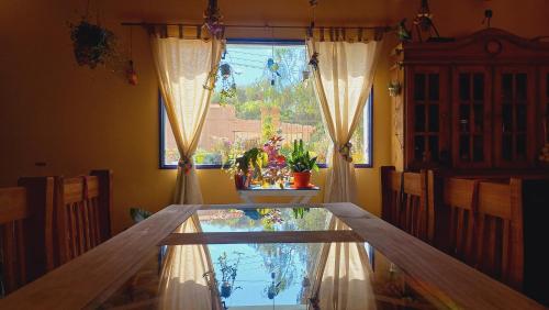 comedor con mesa de cristal y ventana en Casa Munay en Maimará