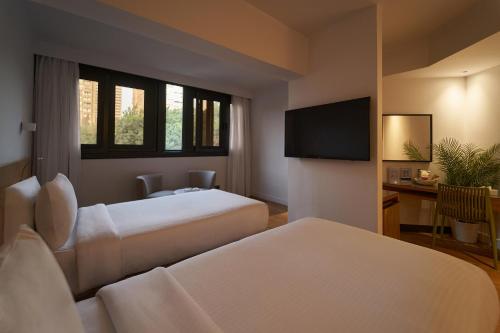 a hotel room with two beds and a flat screen tv at New President Hotel Cairo in Cairo