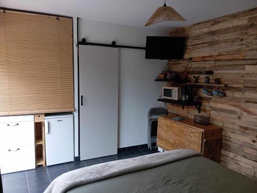 a bedroom with a bed and a tv and a wall at La guitoune in Laroque