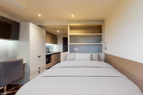 1 dormitorio con 1 cama blanca grande y 1 silla en Private Bedrooms with Shared Kitchen, Studios and 2 Bed Apartments at Canvas Manchester en Mánchester