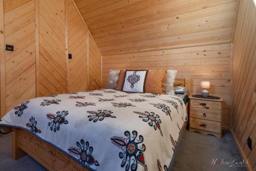 a bedroom with a bed in a wooden cabin at Domek u Hanci z balia na wyłączność in Ząb