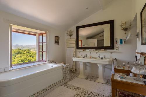 une salle de bain avec une baignoire, un lavabo et une fenêtre dans l'établissement Magnifique maison basque du 18ème avec vue exceptionnelle, à Saint-Pée-sur-Nivelle