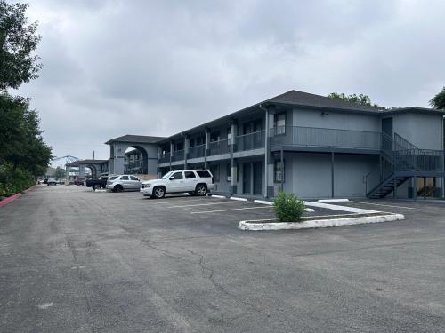 un bâtiment avec des voitures garées dans un parking dans l'établissement Mustang Inn and Suites, à San Antonio