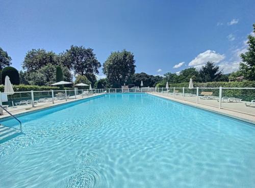 une grande piscine bleue avec des chaises et des arbres dans l'établissement Coup de cœur charmante maison aux bois murés, à Grasse