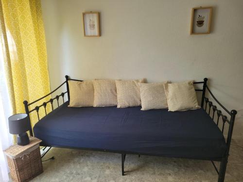 a bed with blue sheets and pillows in a room at Studio en RDC à LAMALOU LES BAINS in Lamalou-les-Bains