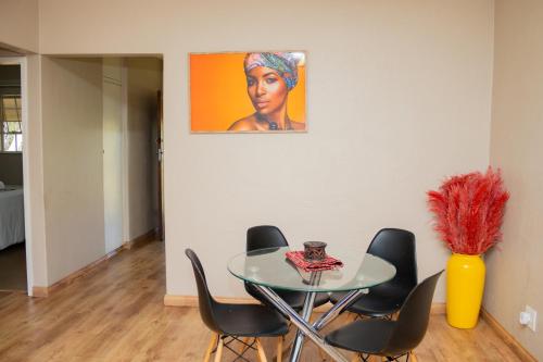 a dining room with a glass table and black chairs at Delightful spacious two bedroom apartment in Johannesburg